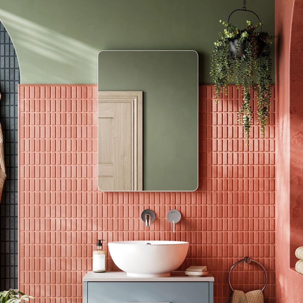 Lifestyle image of the hib. Trim Curve 500mm x 700mm Matt White Bathroom Mirror mounted above a round countertop basin & vanity unit with wall-mounted taps